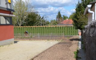 Clôture et réserve d'eau en bordure d'un jardin pédagogique