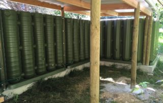 Récupérateurs d'eau de pluie servant de mur pour un abri bois
